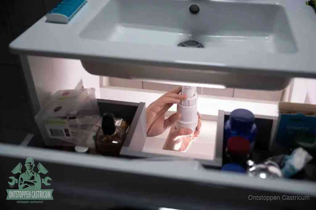 Een pompfles met zeep boven een wastafel, de heet water en afwasmiddel-methode om een vetprop in de afvoer los te maken in Castricum