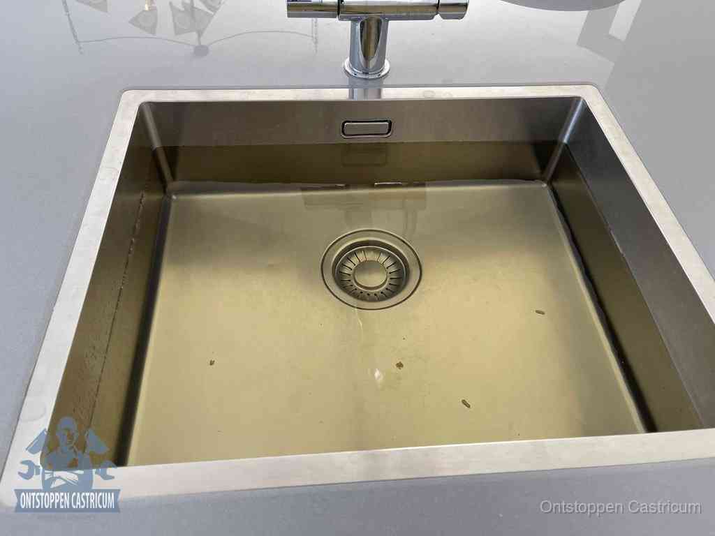 Stilstaand water in een rvs spoelbak dat niet wegloopt, een duidelijk signaal van een gootsteenverstopping in Castricum