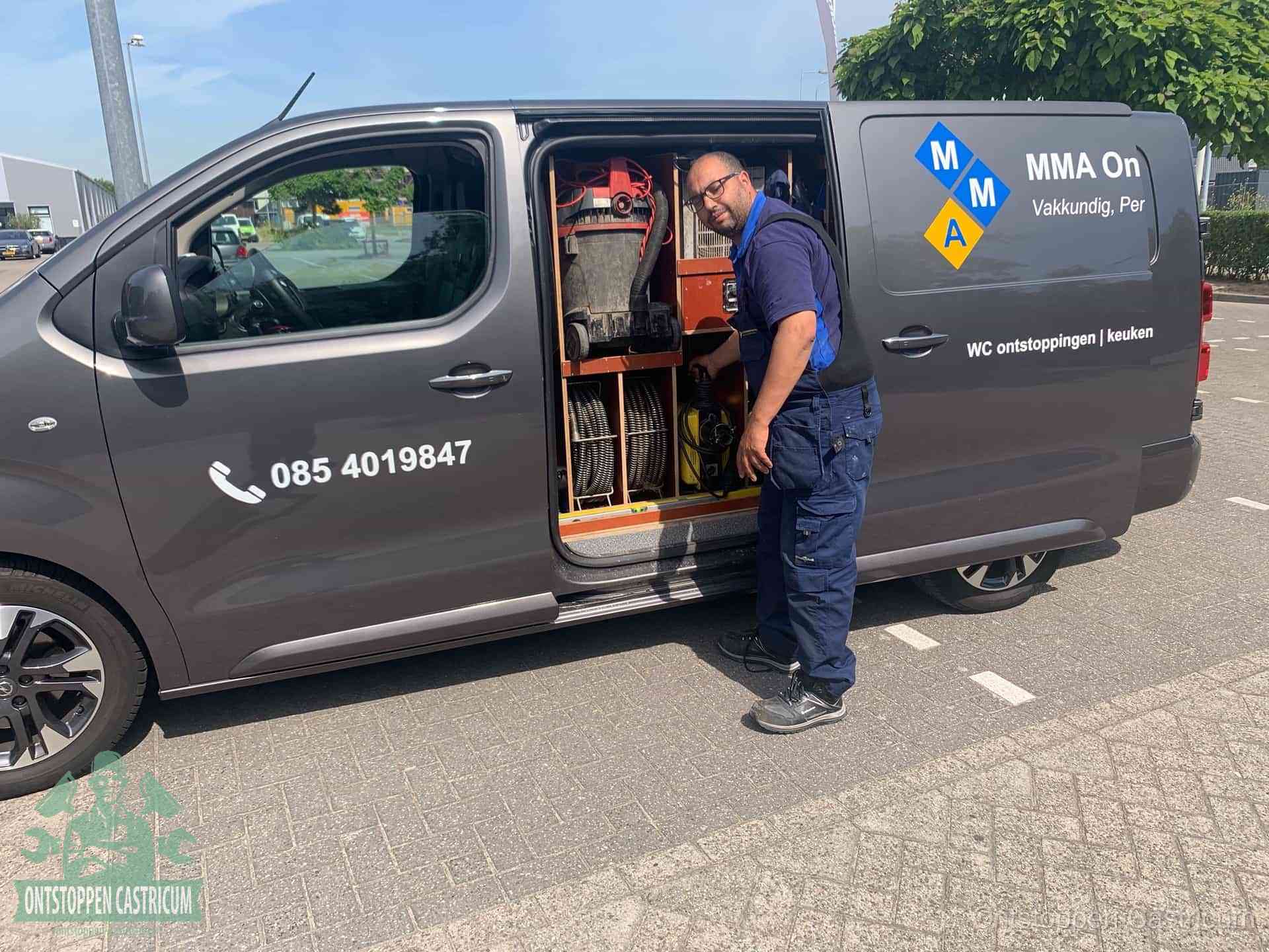 Een monteur bij de open schuifdeur van zijn bedrijfsbus op een parkeerplaats, klaar om de oorzaak van terugkerende afvoerverstoppingen aan te pakken in Castricum