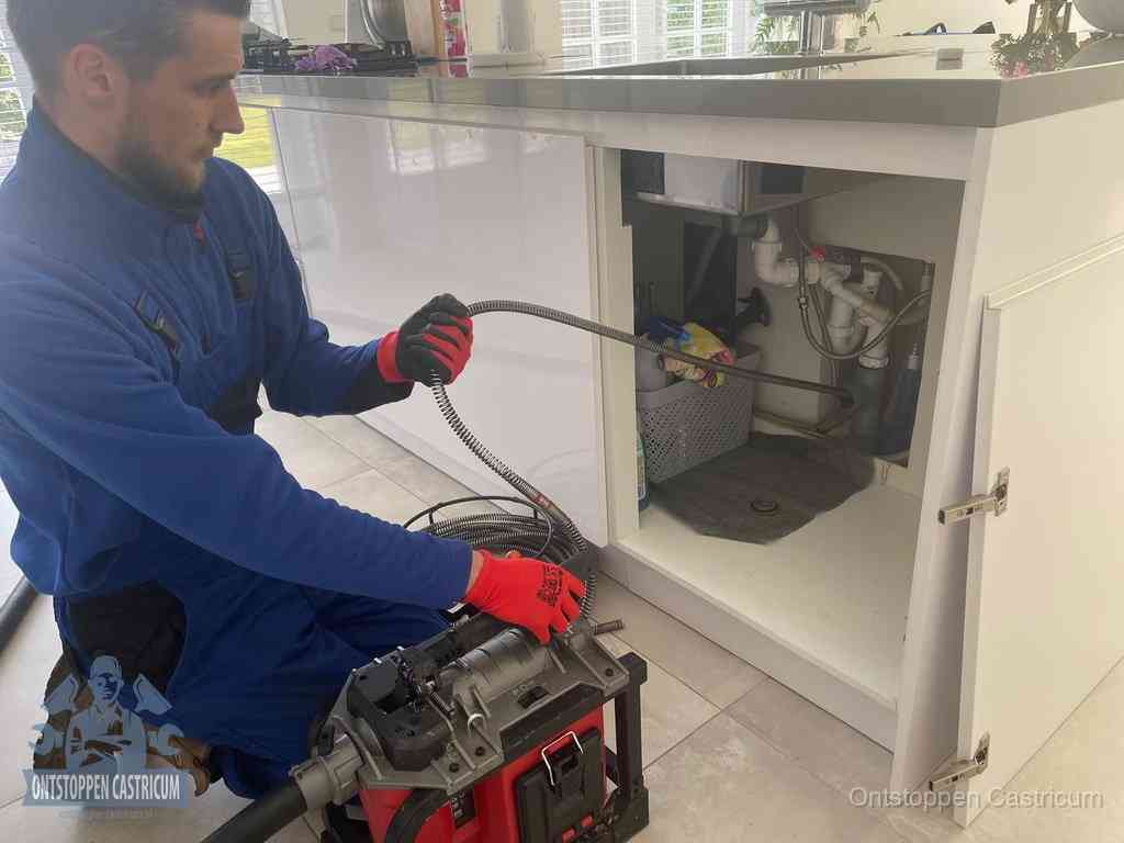 Een monteur reinigt de keukenafvoer grondig met een veermachine om terugkerende gootsteenverstoppingen te voorkomen in Castricum