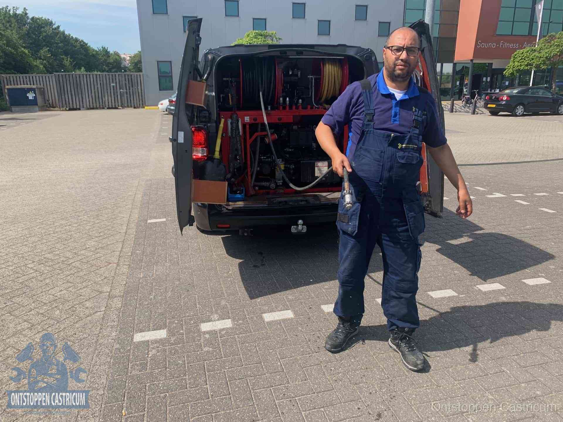 Een monteur bij zijn bestelbus met een hogedruk- en rioolreinigingsunit, klaar om de oorzaak van terugkerende wc-verstoppingen aan te pakken in Castricum