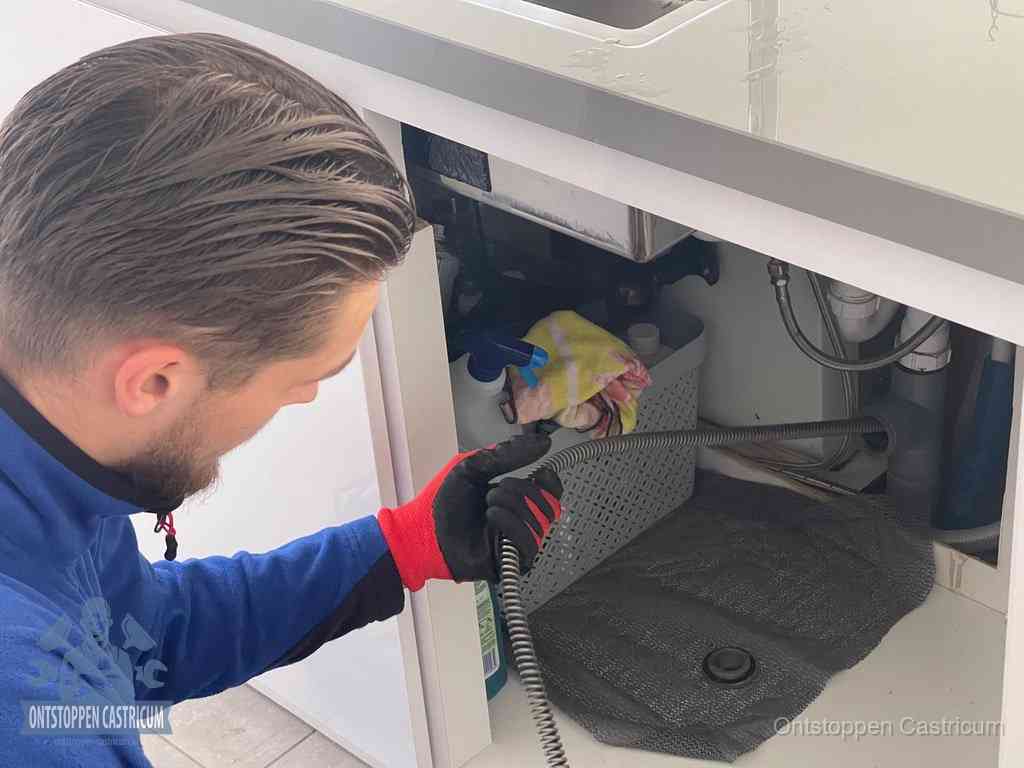 Een monteur voert een flexibele ontstoppingsveer in de afvoer om een verstopping voorbij de bocht van het toilet te bereiken in Castricum
