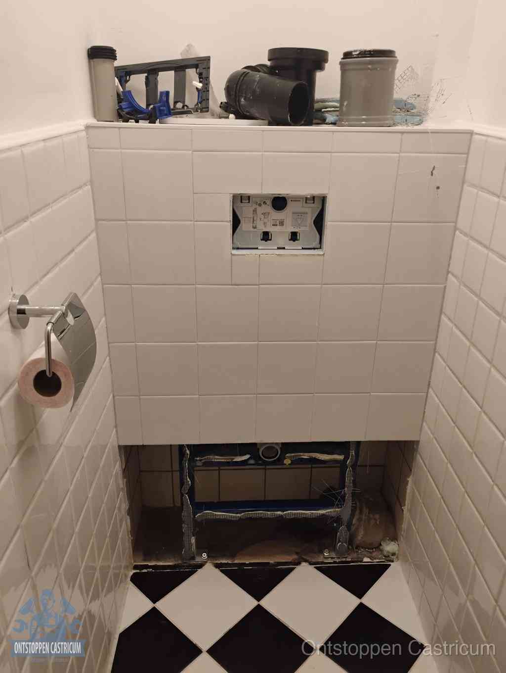 Een toiletruimte waar het hangtoilet en de inbouwreservoir-onderdelen zijn vrijgelegd voor onderhoud, periodiek nazicht voorkomt een wc-verstopping in Castricum