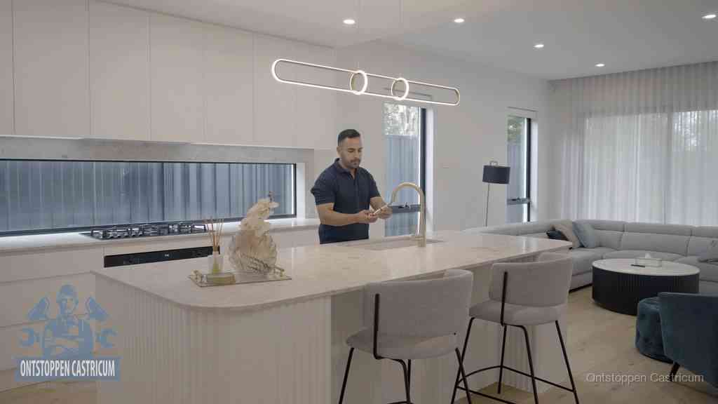 Een bewoner bij de keukenspoelbak die zelf aan de slag gaat met een verstopte gootsteen in Castricum